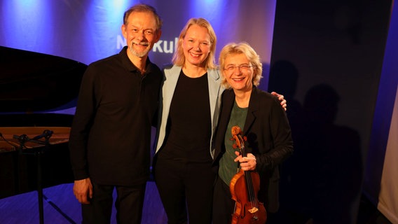 Ein Mann steht links, rechts neben ihm stehen zwei Frauen. © Ekaterina Shurygina / NDR Foto: Ekaterina Shurygina / NDR