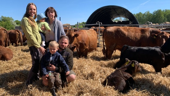 Drei Generationen der Familie Wartmann stehen auf Stroh in einem Außengatter ihrer Rinderhaltung. © NDR Foto: Silke Müller