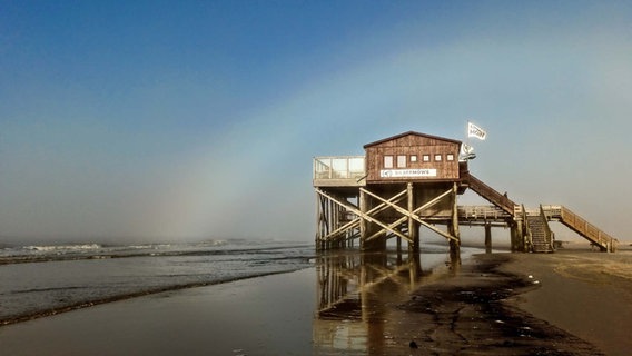 Pfahlbau und blasser Regenbogen am Strand in St. Peter Ordning © Catarina Hey Foto: Catarina Hey